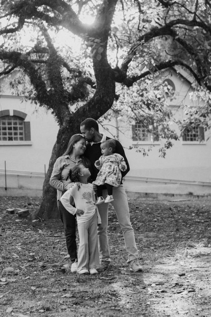 A loving family shares a moment together outdoors surrounded by trees.