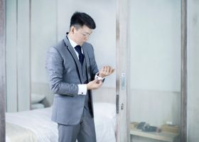 Professional man adjusting cufflinks in a modern gray suit, highlighting corporate style.